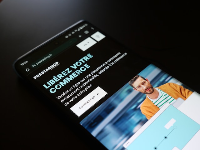 Smartphone affichant la page Prestashop avec le slogan “Libérez votre commerce”, illustrant le e‑commerce et les besoins de financement pour les campagnes publicitaires numériques et la gestion des stocks.