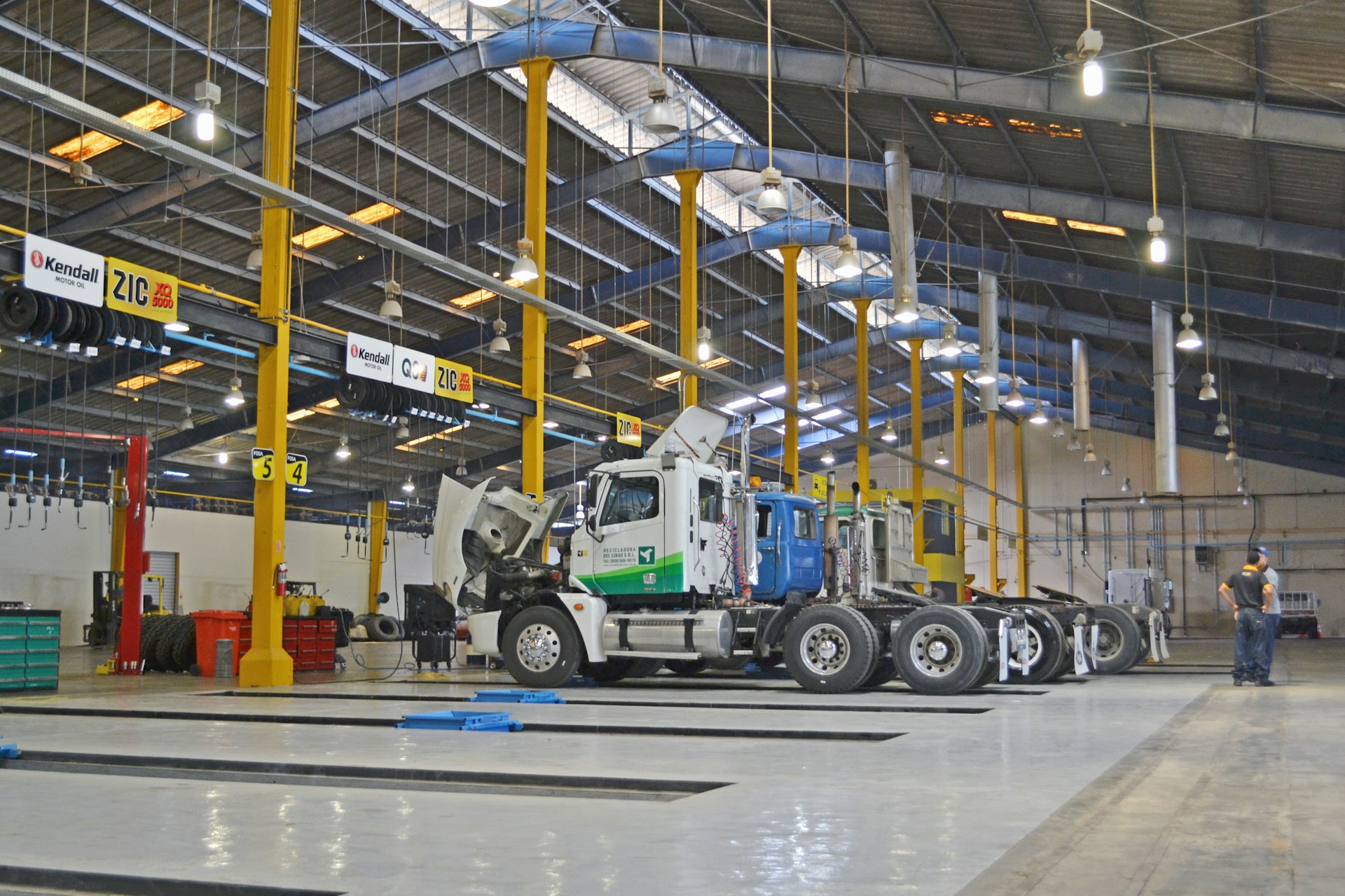 Camion stationné dans un grand garage mécanique, illustrant les besoins en pièces de rechange et en outils de diagnostic.