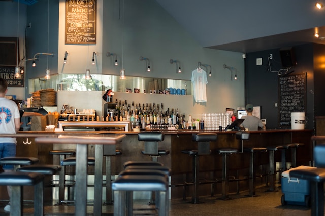 Intérieur d’une microbrasserie à Montréal avec un client et un employé au comptoir, illustrant le secteur de la restauration et de l’hôtellerie et les besoins de financement pour les rénovations, l’achat d’équipement de cuisine et la gestion des saisons creuses.