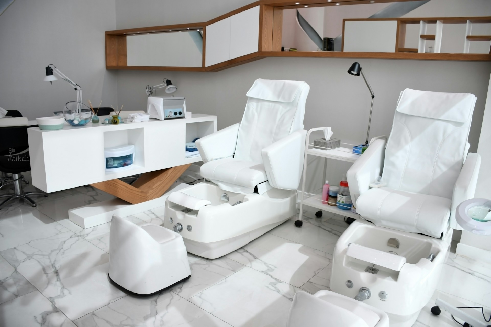 Chaises blanches et bureau en bois dans un salon de beauté moderne, illustrant les rénovations et l’achat de produits de revente.