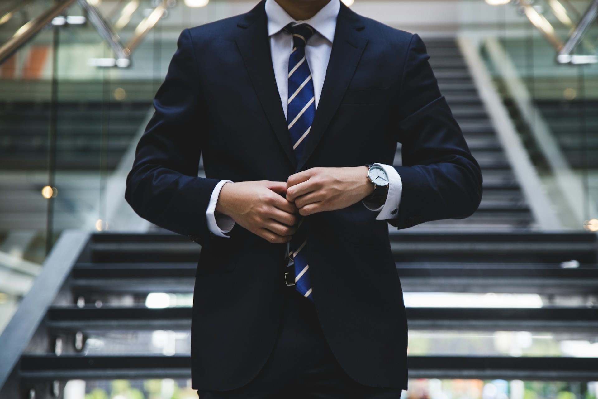 Homme d’affaires descendant un escalier moderne en ajustant son veston, illustrant la croissance d’une entreprise grâce au financement de fonds de roulement.